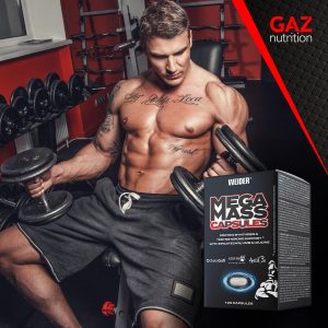 Bodybuilder u teretani izvodi vježbu s bučicama uz prikaz proizvoda Weider Mega Mass Caps.