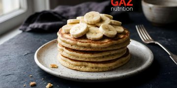 Tri proteinske palačinke s vanilijom ukrašene kolutićima svježe banane na tamnom tanjuru